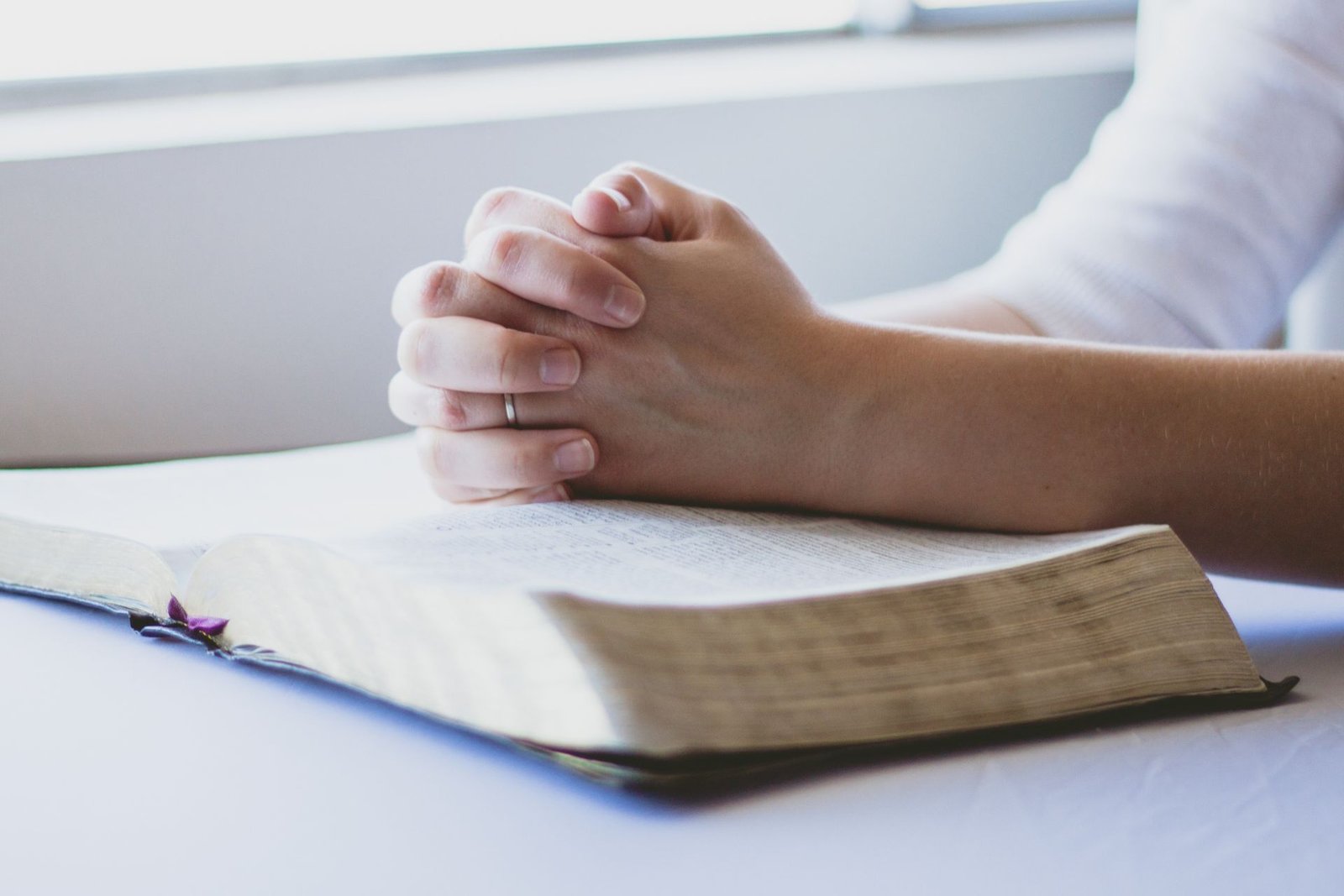 Praying hands resting on a bible