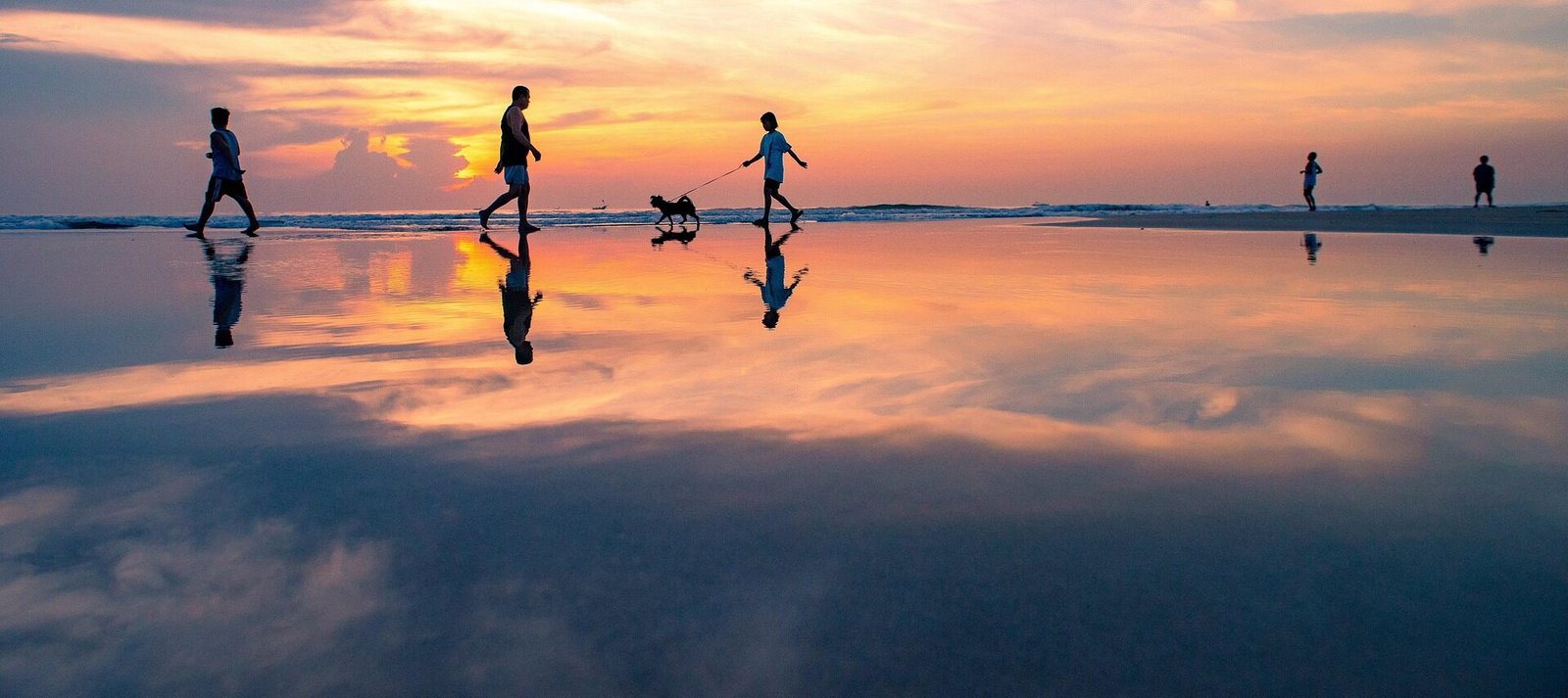 Sunset at the beach with people walking
